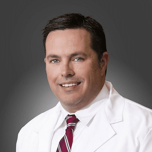 A man in white lab coat and red tie.